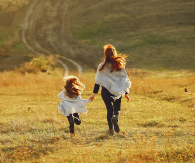 Mother with little daughter playing in a autumn field